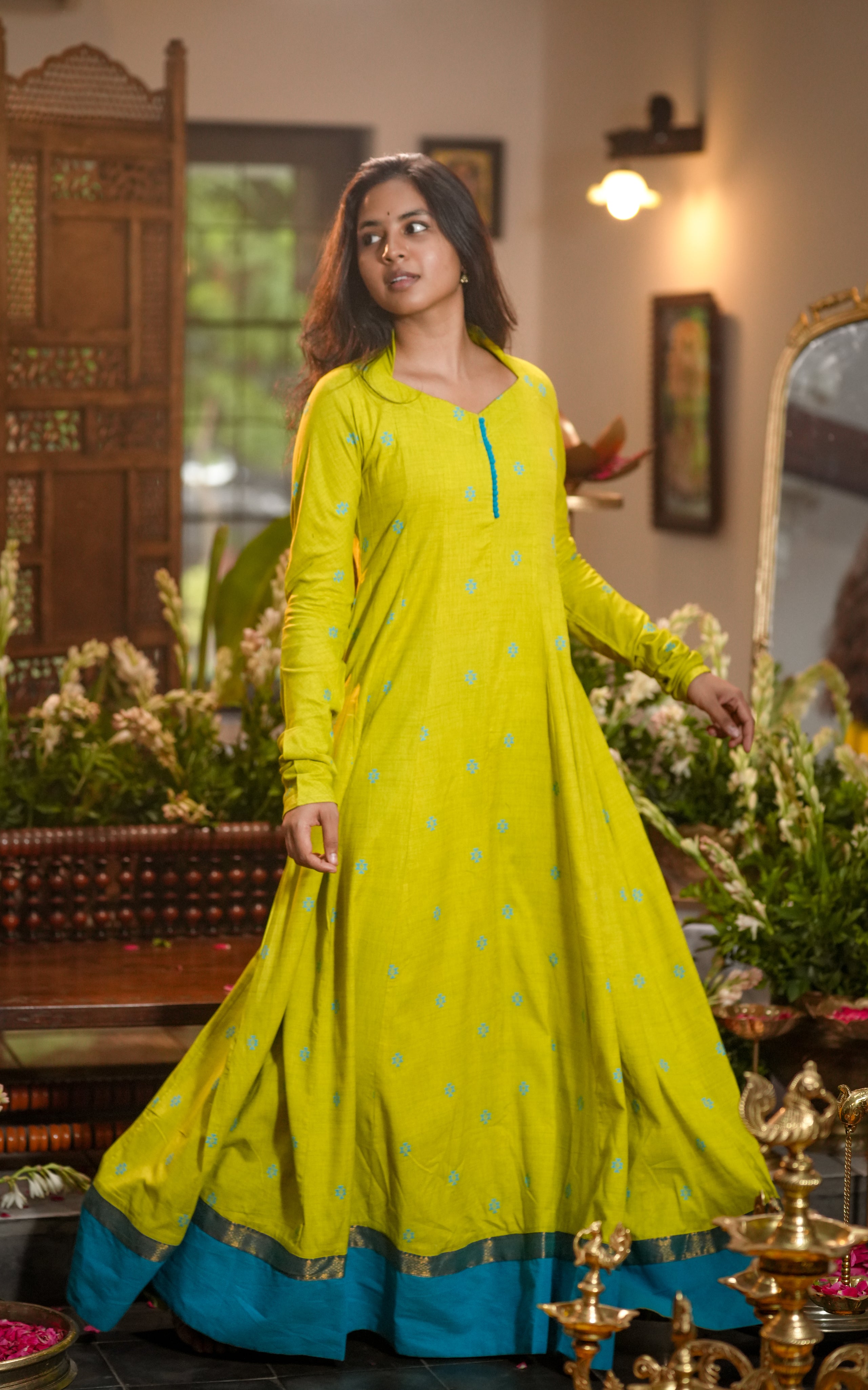 Woman wearing a lime green full-flared South cotton Anarkali with a blue border.