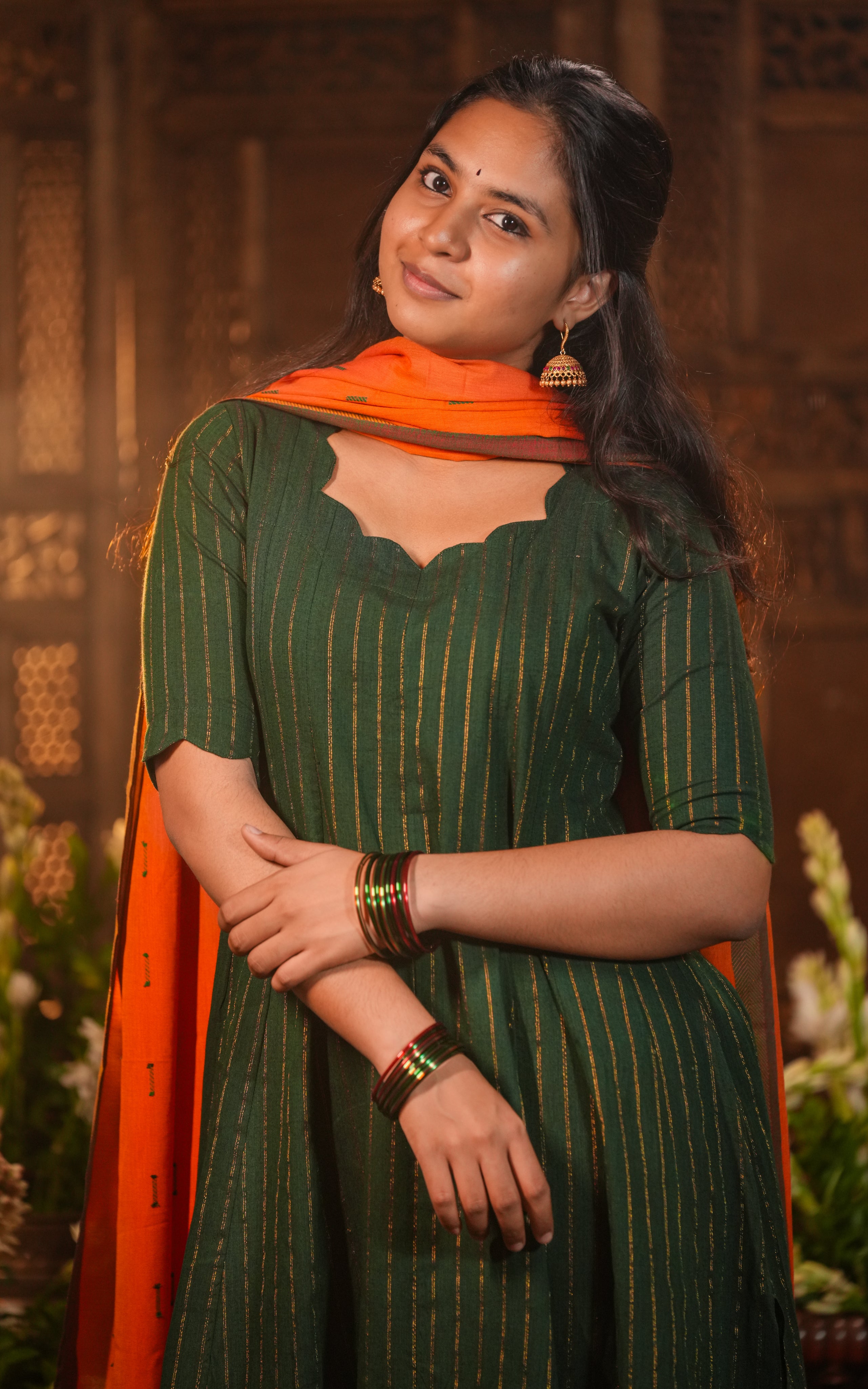 Orange dupatta with subtle golden stripes contrasts beautifully with the green.