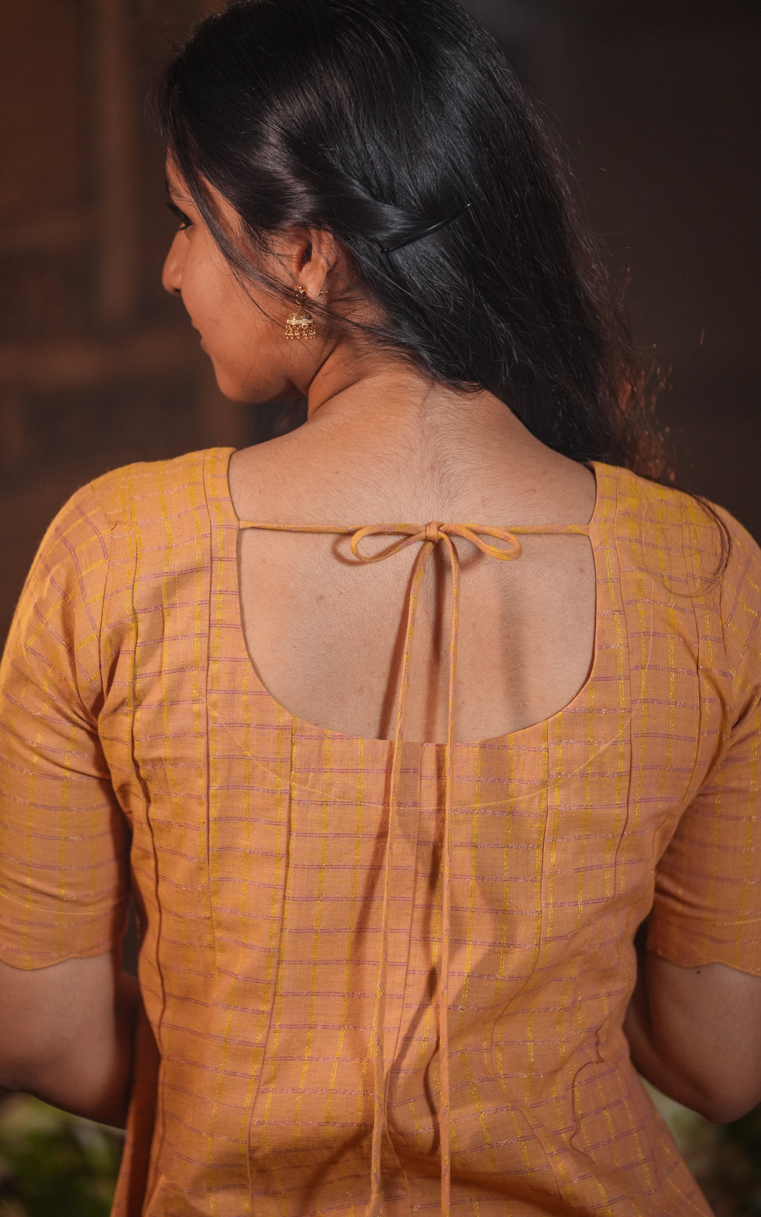 Two slim fabric ties secure the back neckline into a neat bow.