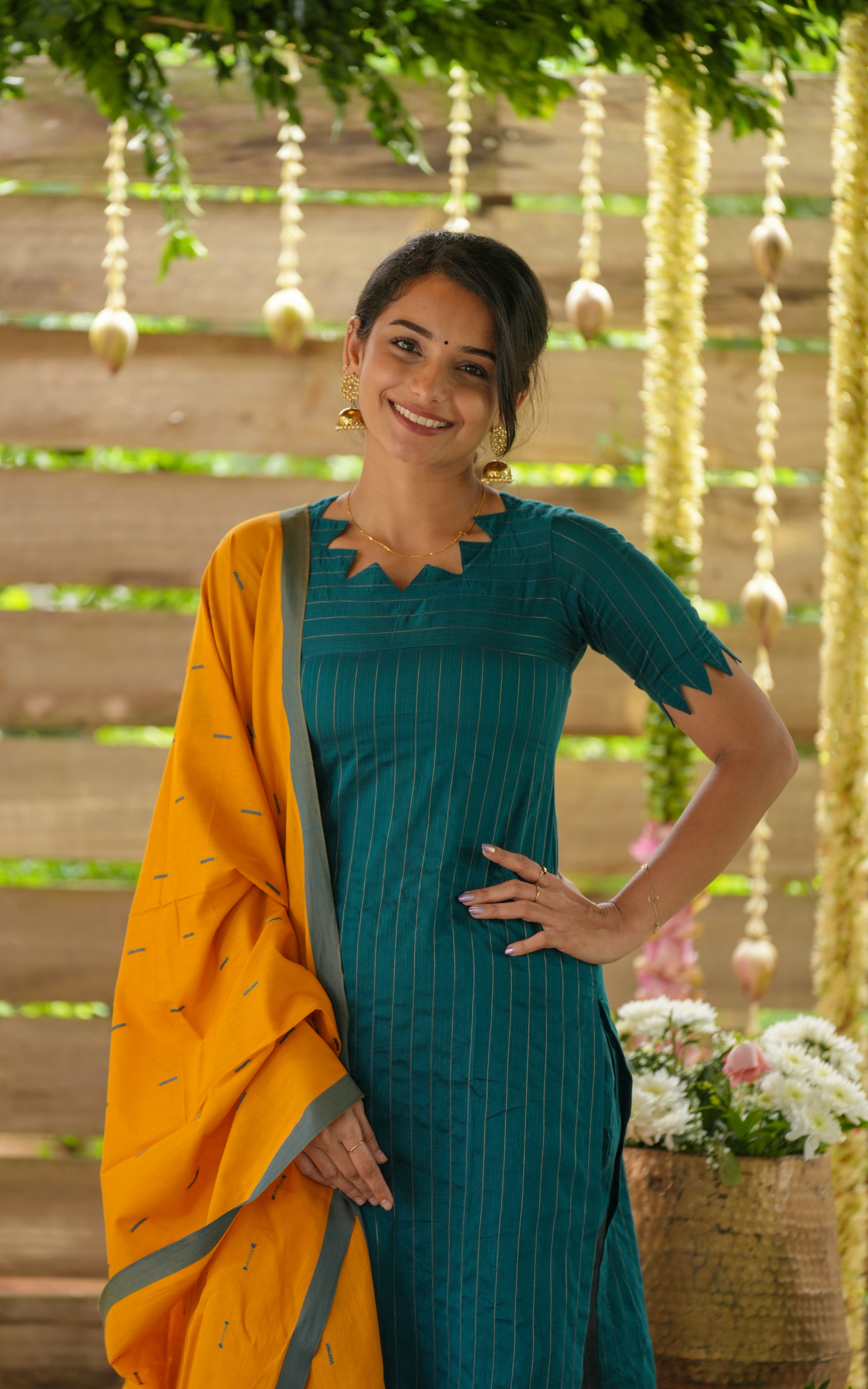 Woman wearing a teal and Yellow traditional outfit .