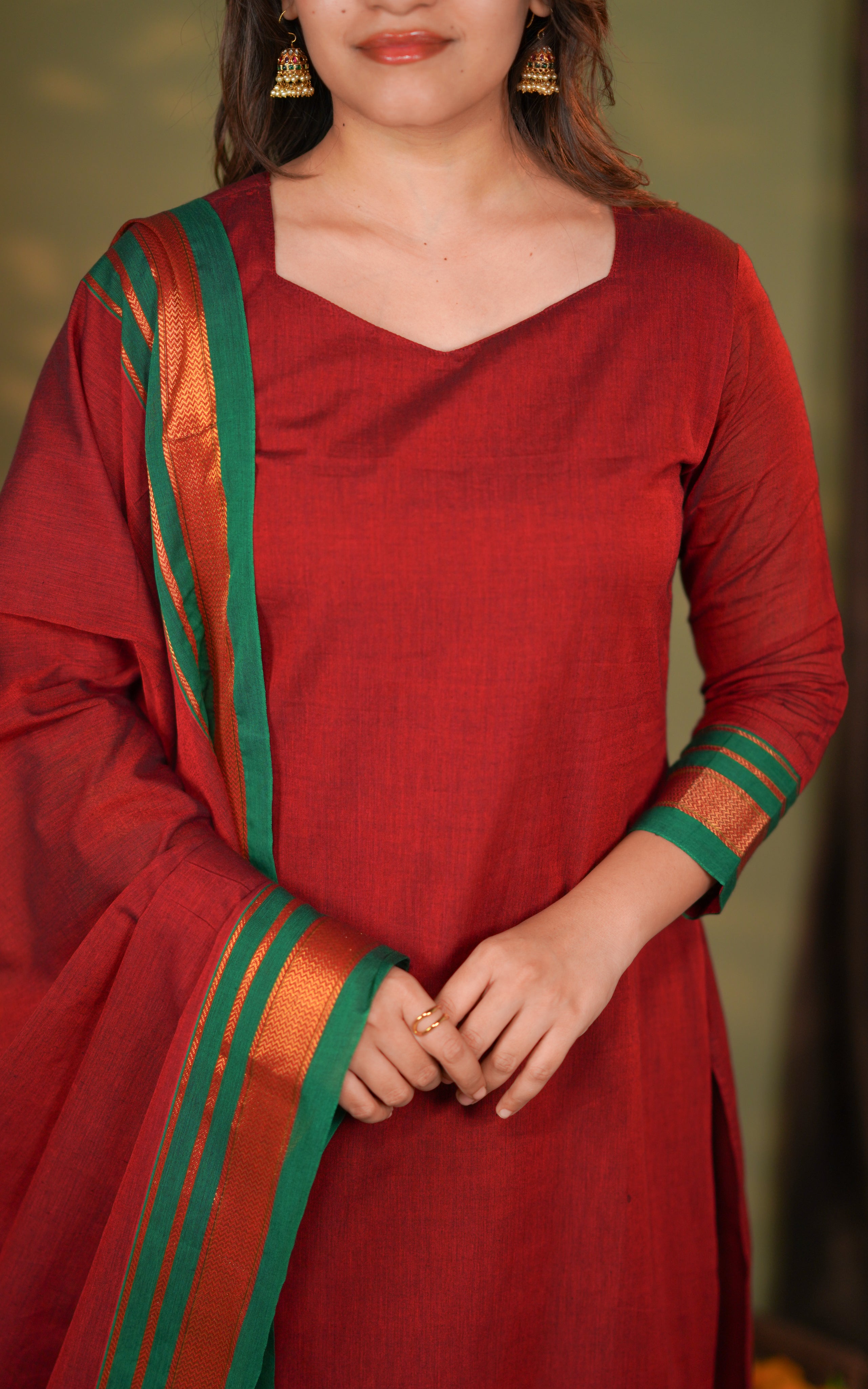 A matching maroon dupatta in Nyranapet fabric carries bold green and gold stripes for a luxurious ethnic touch