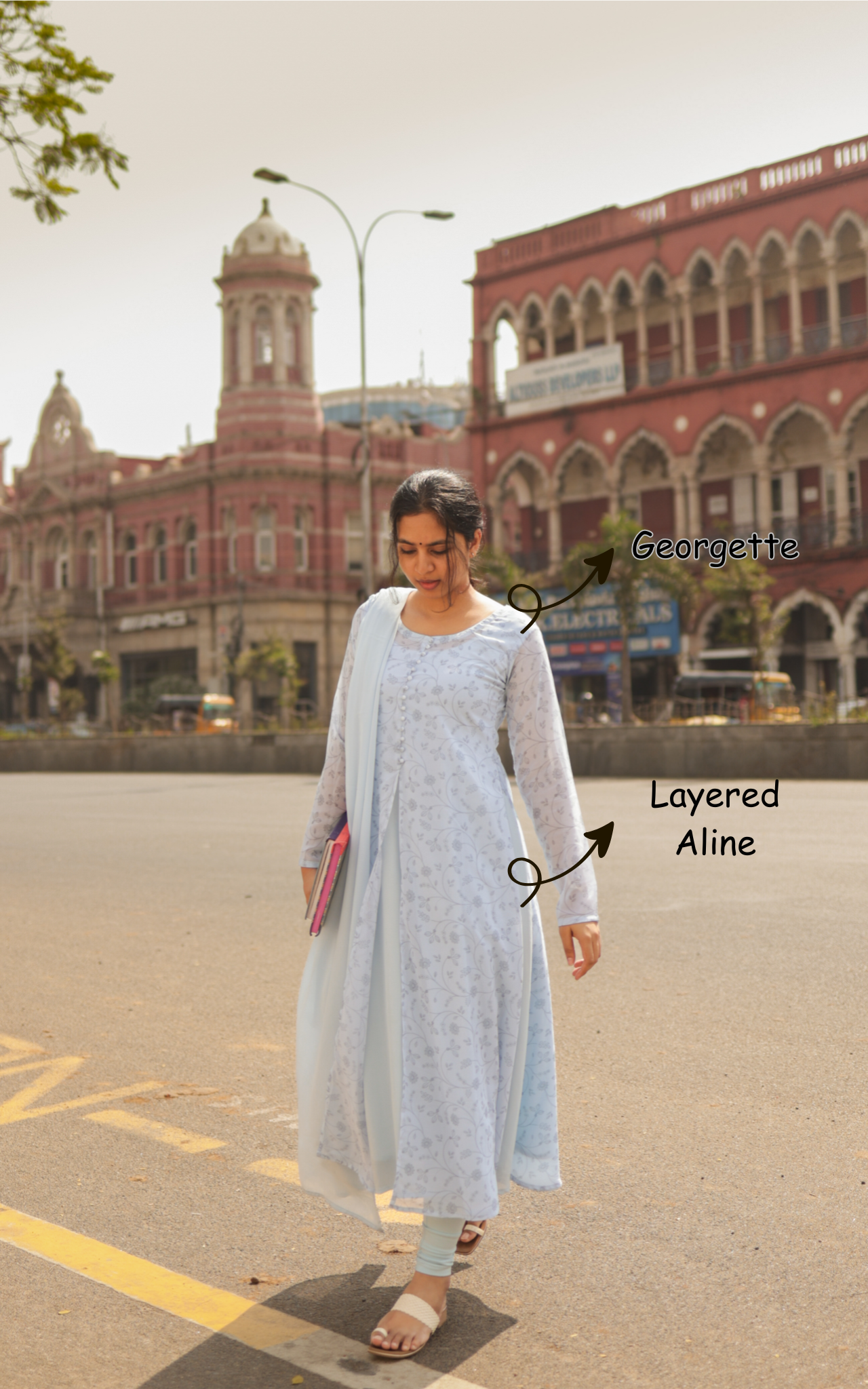 Woman wearing a light blue georgette layered A-line dress in an urban setting.