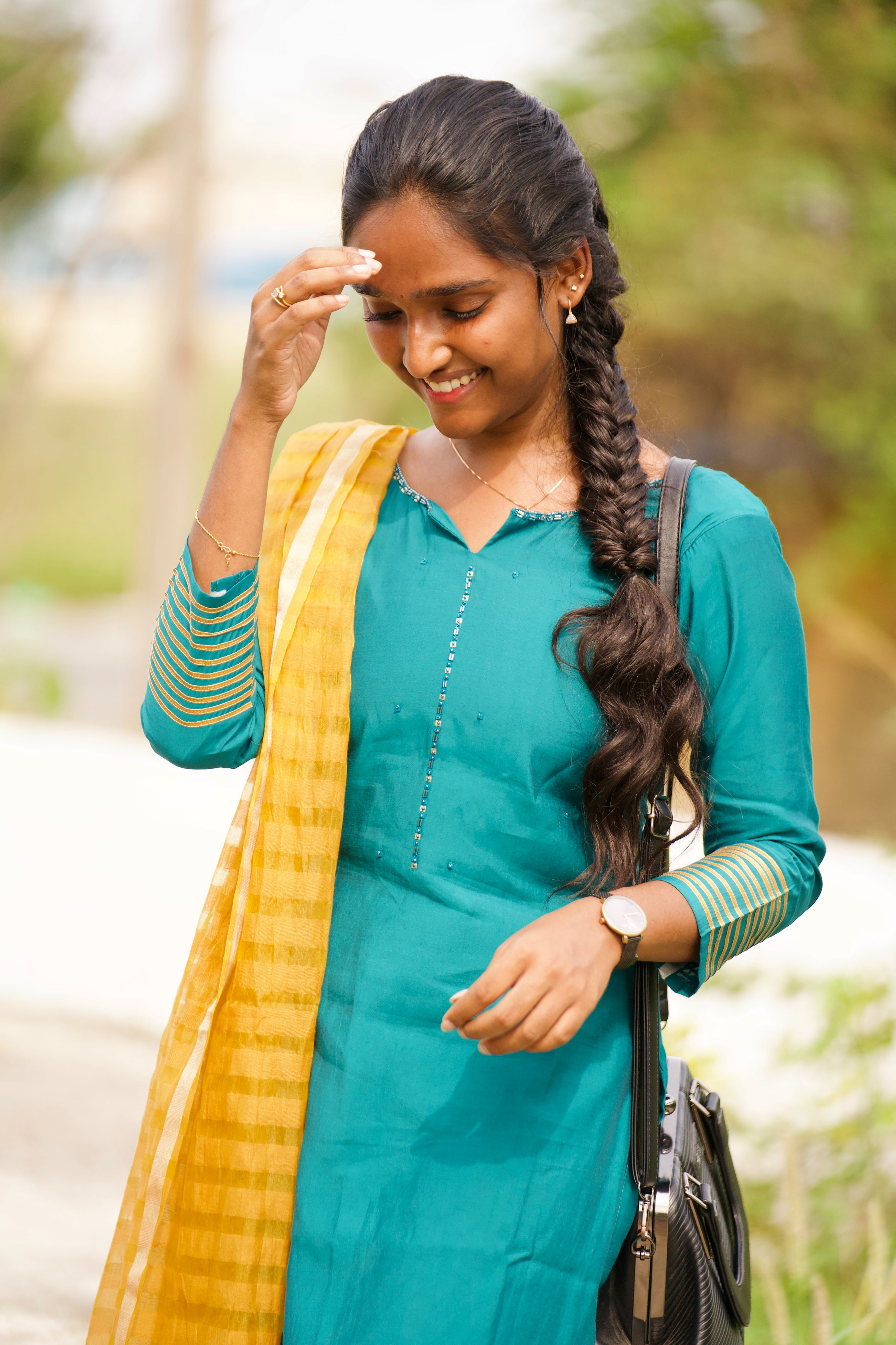 Woman in teal outfit with yellow dupatta outdoors