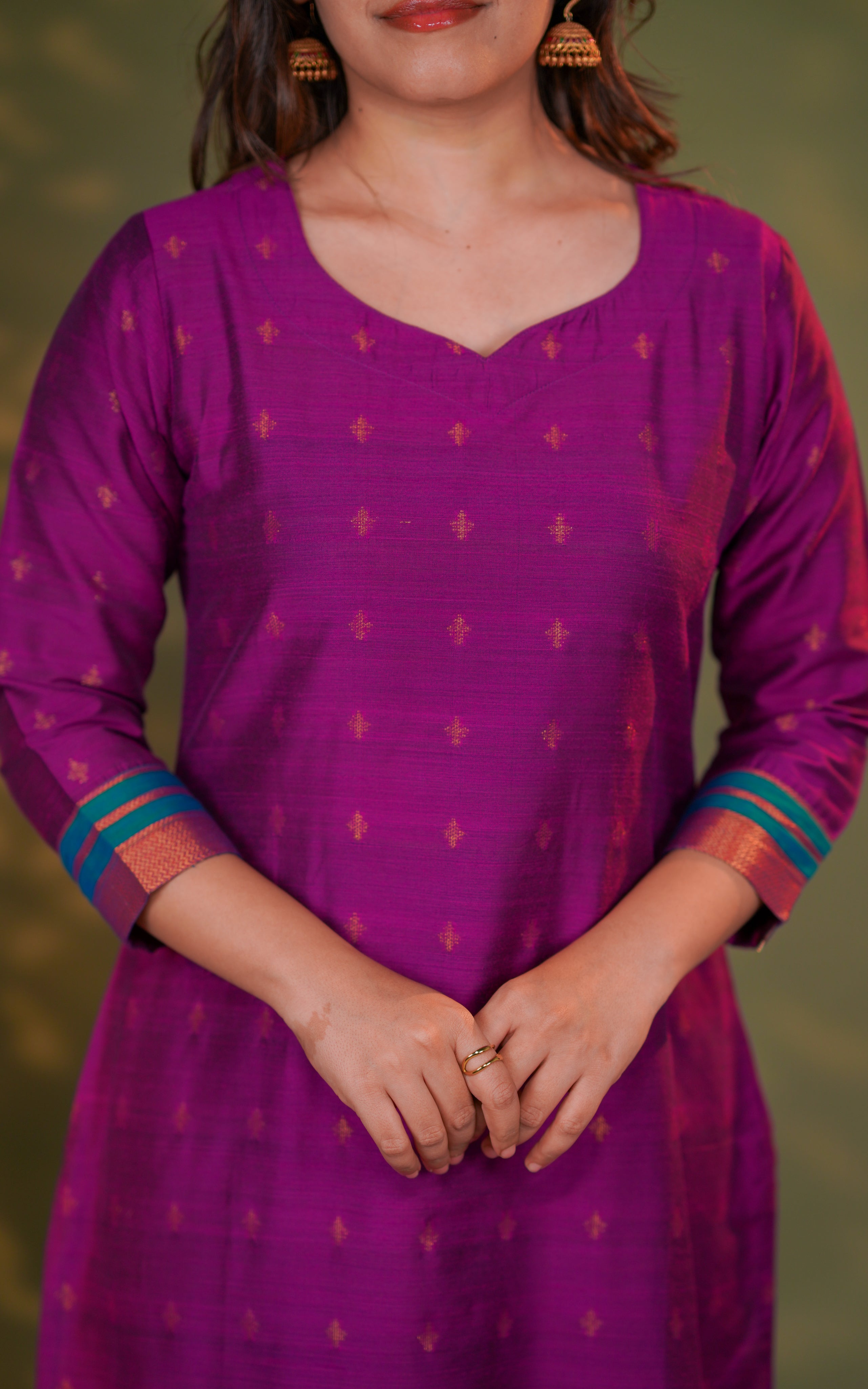 hemline is detailed with matching teal and gold stripes that add a premium ethnic feel. Side slits are included for comfortable movement and better fit. The fabric has a soft sheen that elevates the overall luxurious appearance.